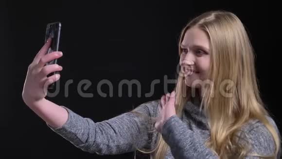 黑色背景的智能手机上金发的直发女孩在视频游戏中愉快地交谈的肖像视频的预览图