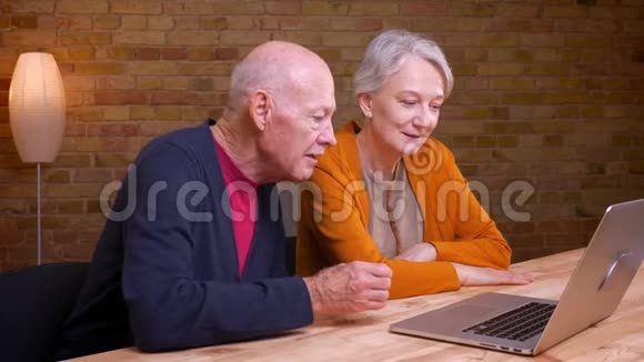 两位白发苍苍的老白种人夫妇在笔记本电脑上用视频聊天在办公室里很开心视频的预览图