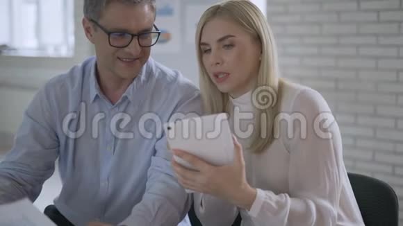 商人在平板电脑上看金融图表商务会议同事在后台说话视频的预览图
