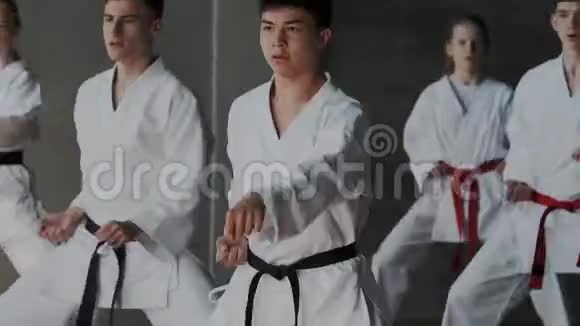 一群年轻的男女运动员在跆拳道学校练习武术白色和服专注的头脑和脸视频的预览图