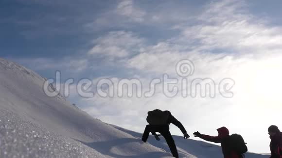 侍从们互相动手帮助一个朋友爬到雪山的顶端团队合作渴望赢得视频的预览图