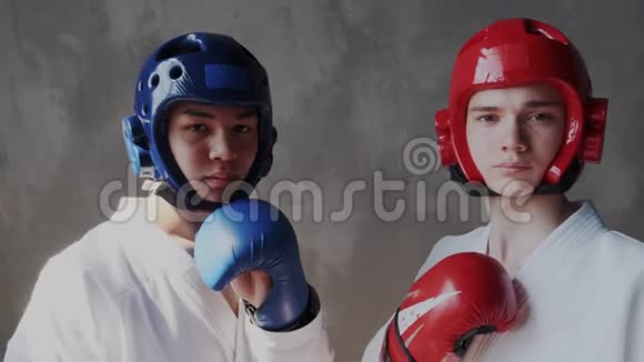 多民族的两个勇敢自信的拳击手穿着和服戴着红蓝相间的手套和防护头盔视频的预览图