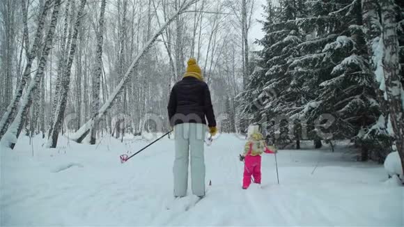 女孩在雪地里和妈妈一起滑雪视频的预览图