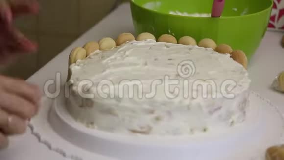 一个女人装饰一个萨沃亚迪饼干蛋糕把饼干放进蛋糕圈视频的预览图