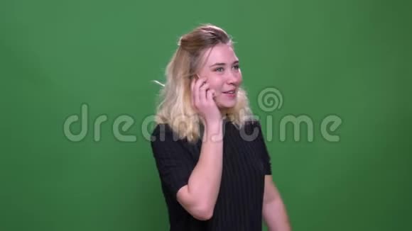 一位年轻漂亮的白种人女性的特写照片她打电话时背景与绿色隔离视频的预览图