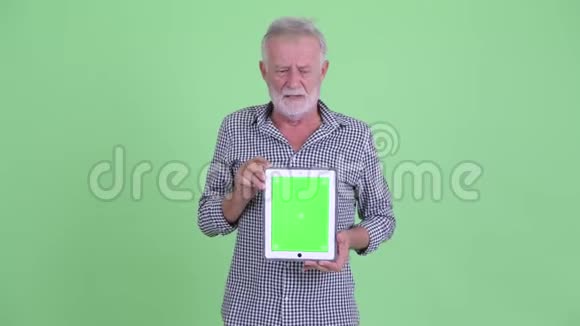 戴着大胡子的老人展示数码平板电脑并得到坏消息视频的预览图