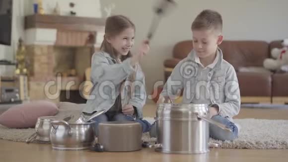兄妹二人演奏音乐家用大勺子敲打锅碗瓢盆开怀大笑视频的预览图