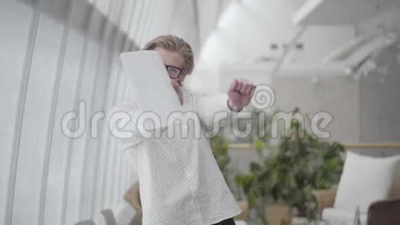 金发快乐的男人戴着眼镜在一间轻松舒适的办公室里跳舞手里拿着文件老板把文件丢了视频的预览图