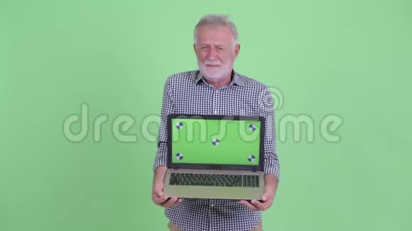 戴着大胡子的老人展示笔记本电脑并得到坏消息视频的预览图