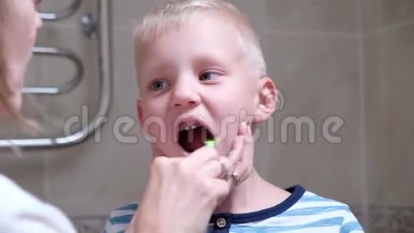 特写母亲早上帮助她的小儿子清洁牙齿女人帮儿子刷牙视频的预览图