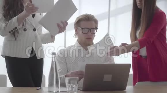 紧张的男人坐在舒适的办公室里桌上放着上网本检查两个女同事的文件视频的预览图