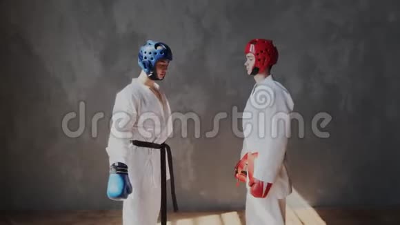 两个年轻强壮的青少年戴着防护头盔和拳击手套热身肌肉采取战斗姿势看着视频的预览图