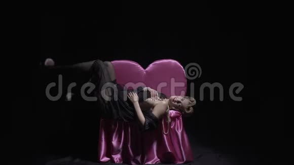 从50年代开始的性感别针模特躺在粉红色的沙发上4k视频的预览图
