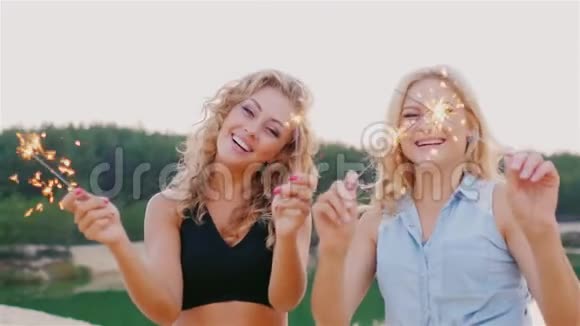两个有魅力的女人带着火花在海滩上大笑视频的预览图