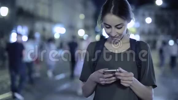 年轻漂亮的女人手拿着电话站在利沃夫市中心拥挤的街道上时间流逝的视频视频的预览图