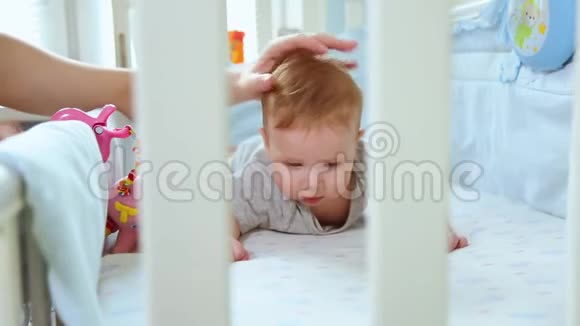 特写妈妈和一个小孩在婴儿床上玩笑着从婴儿床的格子里看到侧面快乐的童年视频的预览图