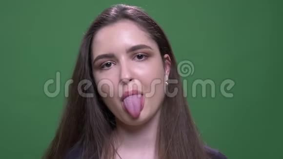 年轻漂亮的深色头发的女性的特写照片露出舌头用相机做出滑稽的面部表情视频的预览图