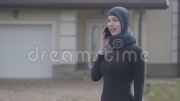 一位年轻美丽的穆斯林妇女戴着黑色头饰在户外用手机交谈的肖像可爱的亚洲女孩视频的预览图