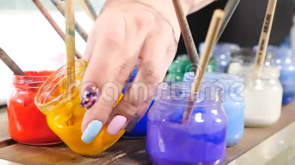 五颜六色的玻璃瓶里面有明亮的油漆在罐子里画刷子许多不同的丙烯酸涂料在罐子附近视频的预览图