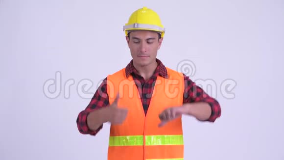 年轻迷茫的西班牙男子建筑工人在竖起大拇指和竖起大拇指之间做出选择视频的预览图