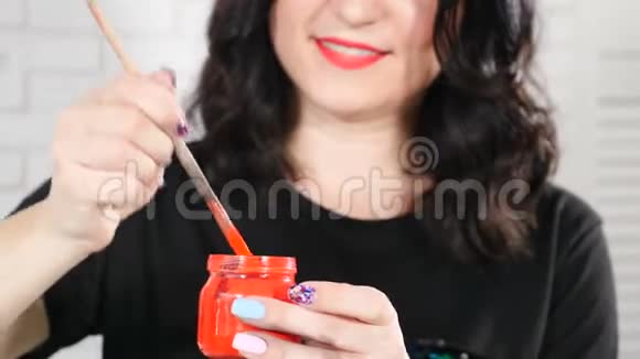 幸福女画家的肖像玻璃罐子里有红色的油漆从刷子上掉油漆水彩画视频的预览图