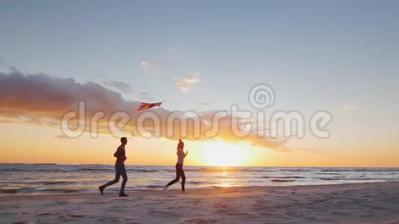 年轻夫妇在日落时在海滩上玩风筝斯特迪纳姆慢镜头视频的预览图