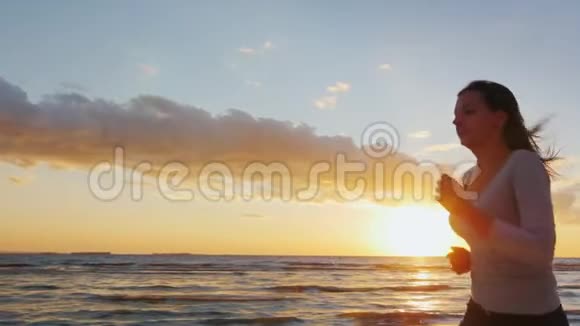 迷人的年轻女子在日落时沿着海滨奔跑从事运动健康的生活方式慢吞吞视频的预览图