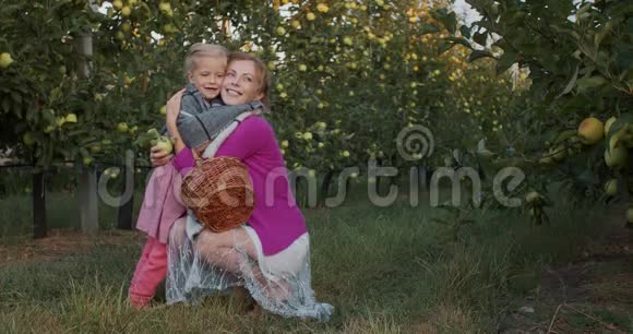苹果园的母亲和女儿拥抱着微笑着视频的预览图