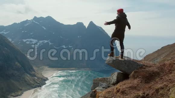 挪威的一个徒步旅行者站在山的边缘风很大视频的预览图