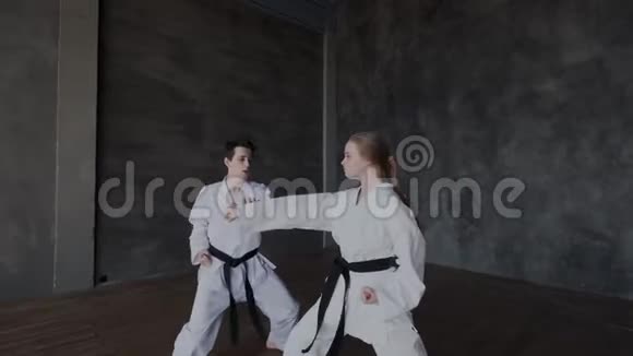 一个黑发男人和一个金发女孩在科莫诺练习黑带战斗艺术时的慢动作视频的预览图