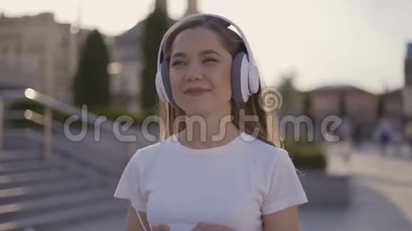 平静的女孩走在城市里清晨戴着4K纸杯大耳机的女人视频的预览图