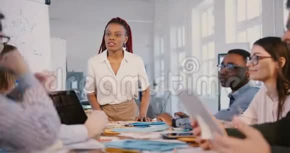美丽的年轻黑人商业女性领袖在金融专家教练研讨会上与多民族员工交谈视频的预览图