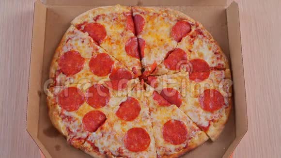 人手从打开的盒子里取出一片美味的意大利热比萨饼在宴会上提供送餐服务视频的预览图