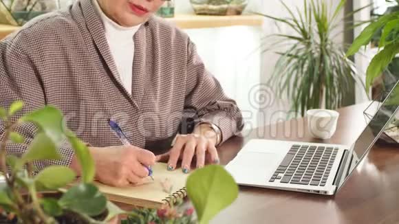 戴眼镜的老妇人坐着笔记本电脑写着笔记本视频的预览图