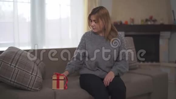 胖女人在沙发上找到了留给她的礼物女孩用红丝带打开盒子惊讶于是什么视频的预览图