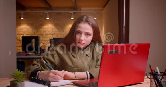 年轻少女写在笔记本上的肖像集中在办公室里视频的预览图