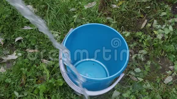在夏天的花园里那个人把水倒进一个塑料蓝色的水桶里视频的预览图
