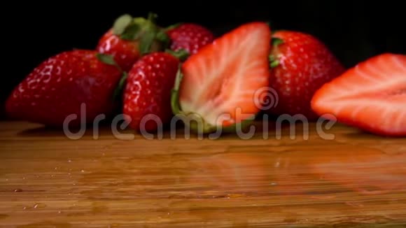 美味的草莓落在潮湿的木板上视频的预览图