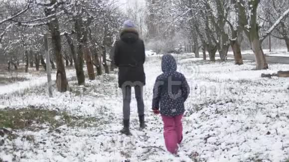 妈妈带着一个女儿在春天多云的公园里散步下雪了视频的预览图