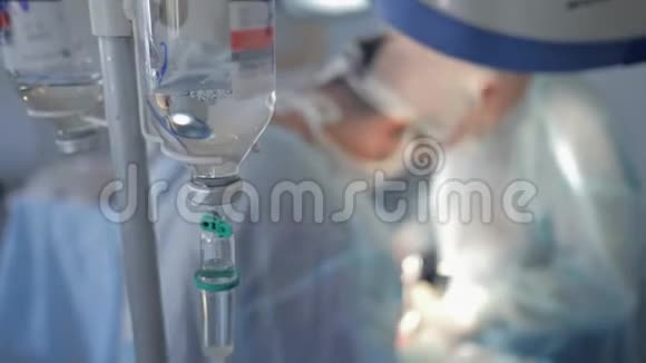 药物从瓶子中滴入焦点外科医生命令在焦点以外的背景下对病人进行手术视频的预览图