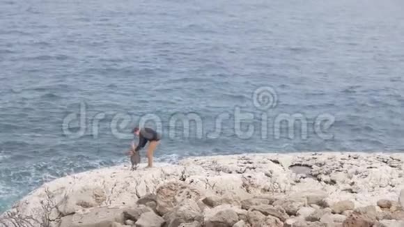 一个男人和他的小女儿站在一块白色的岩石上看着大海视频的预览图