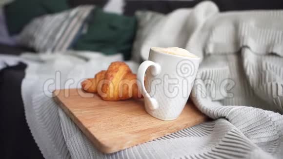 白色杯子里的咖啡和舒适沙发上的新鲜羊角面包在寒冷的冬天吃早餐舒适的概念视频的预览图