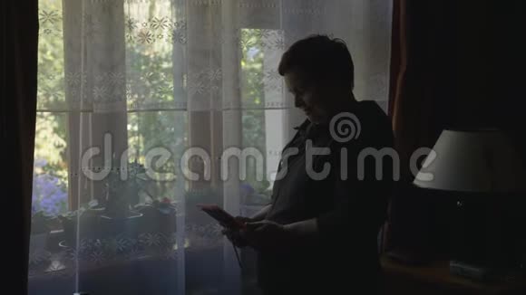 站在窗前一位老妇人拿着一张画框看着她抚摸着他的手视频的预览图