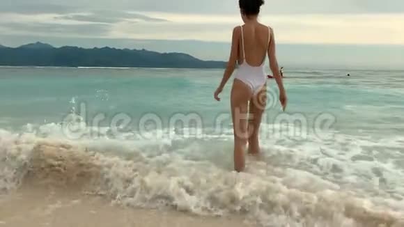 穿着泳衣的美女在热带海滩的海浪中飞溅视频的预览图