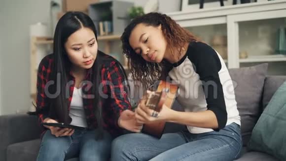 亚洲女士用笔记本电脑教她的非裔美国朋友一起弹吉他学习女孩视频的预览图