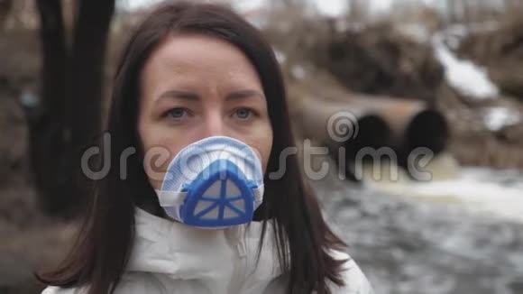 女士佩戴真正的防污染化学物质排入河流和病毒面罩管道里脏污水视频的预览图