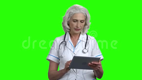 严重的医生与平板电脑在绿色屏幕上视频的预览图