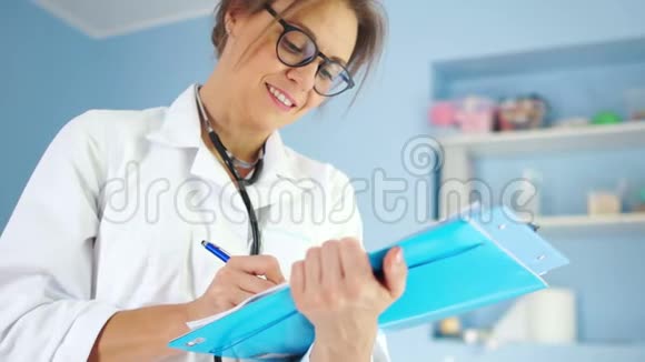 女医生写下病人的病历医生穿着一件白色的医用长袍戴着眼镜视频的预览图