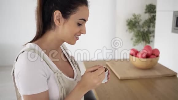 漂亮的年轻孕妇在家厨房里吃冰淇淋时用手机视频的预览图