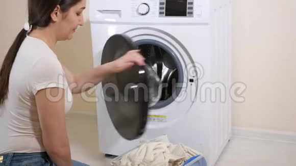 女人把衣服放进坐在地上的洗衣机里视频的预览图
